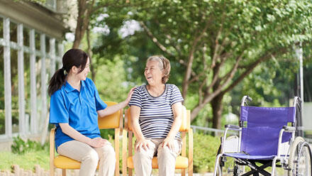 椅子に座って笑いあう介護職と利用者