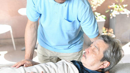 ベッドで眠る高齢者に寄り添う介護職