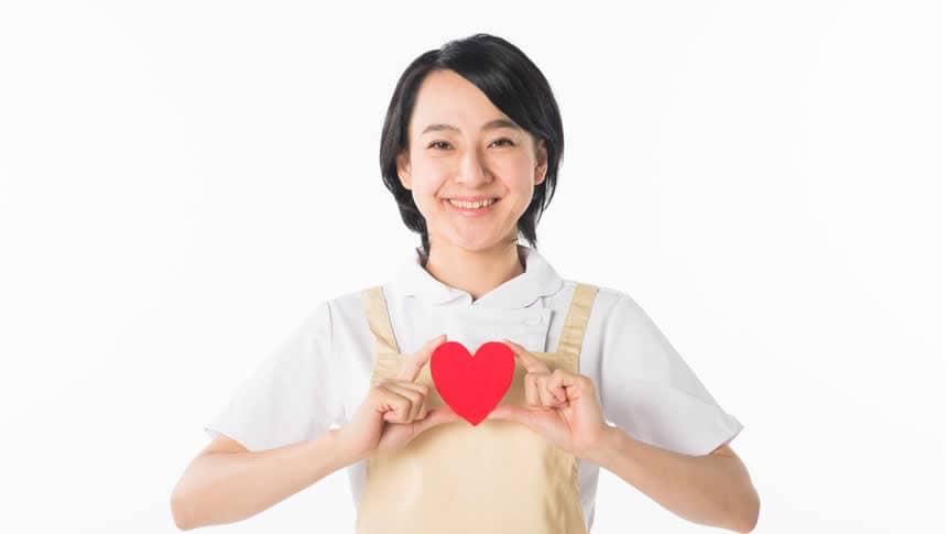 ハートを胸元にかかげ微笑む介護職員