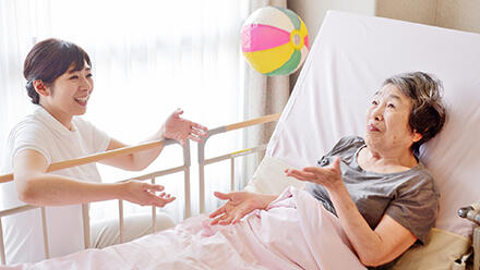 ベッドの上で紙風船で遊ぶ高齢者