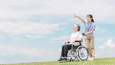 車いすの高齢者と遠方を指さす介護職