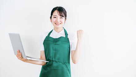 ノートパソコンを手にガッツポーズをする女性