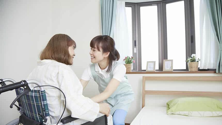 車イスからベッドへ移乗介助する介護士