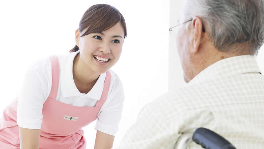 車いすに乗っている利用者に微笑みかける介護職員