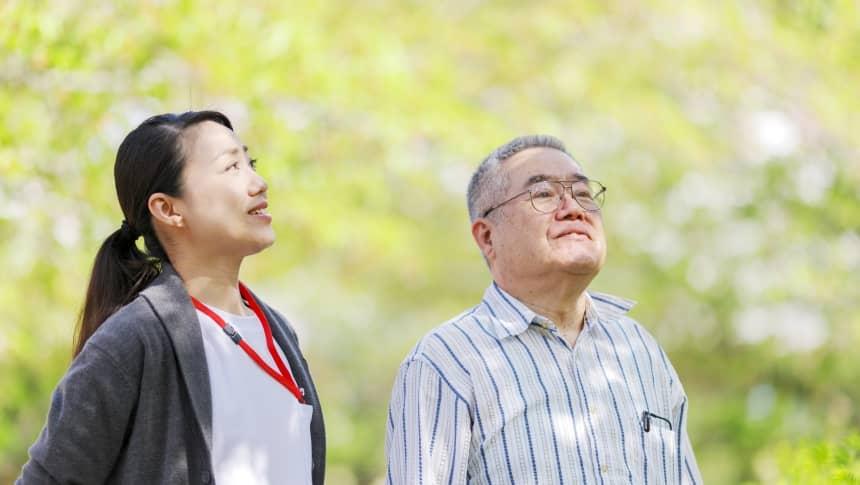 新緑の中の介護士と利用者