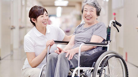 車いすの高齢者と寄り添う女性